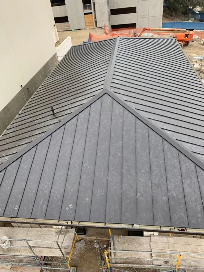 Commercial metal roof construction with crane equipment in Quincy